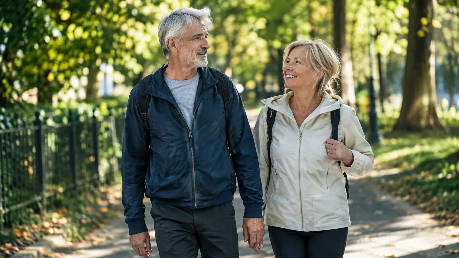 An older couple walking together on a tree-lined path in the morning